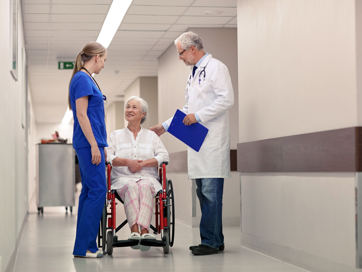 Arzt im Gespräch mit Patientin im hellen Klinikflur