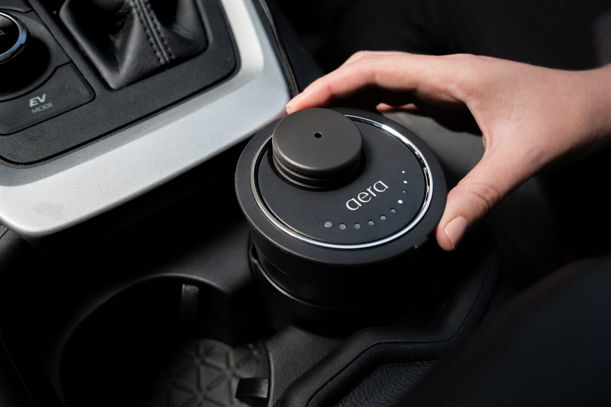 AERA Car im Getränkehalter der Mittelkonsole, eine Hand stellt die Intensität ein